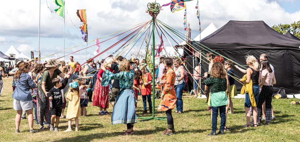 Multiple people dancing around a may pole at purbeck valley folk festival 2021.