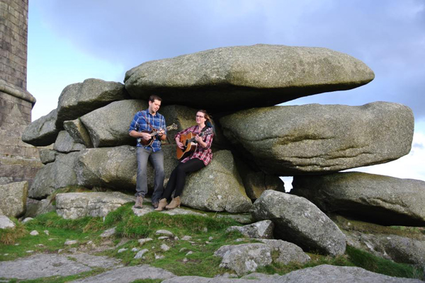 Jacey & Dan leaning up against some large rocks with their instruments