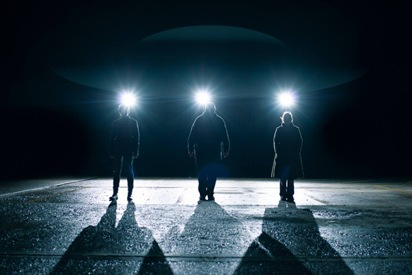 three silhouettes that are backlit by what looks like a UFO