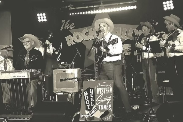 The Boot Heel Playboys image. A faded sepia tone image of the band playing live on stage. 