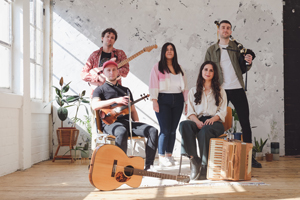 Eabhal image. The band are in a neutral looking studio space. There are 5 of them posing with their instruments.