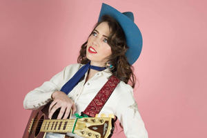 Martha Spencer and the Wonderland Country Band image. </p>
<p>Martha is posing with her guitar, with a bubblegum pink background
